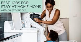 A smiling woman who is folding laundry while a small boy kneels beside her and watches.